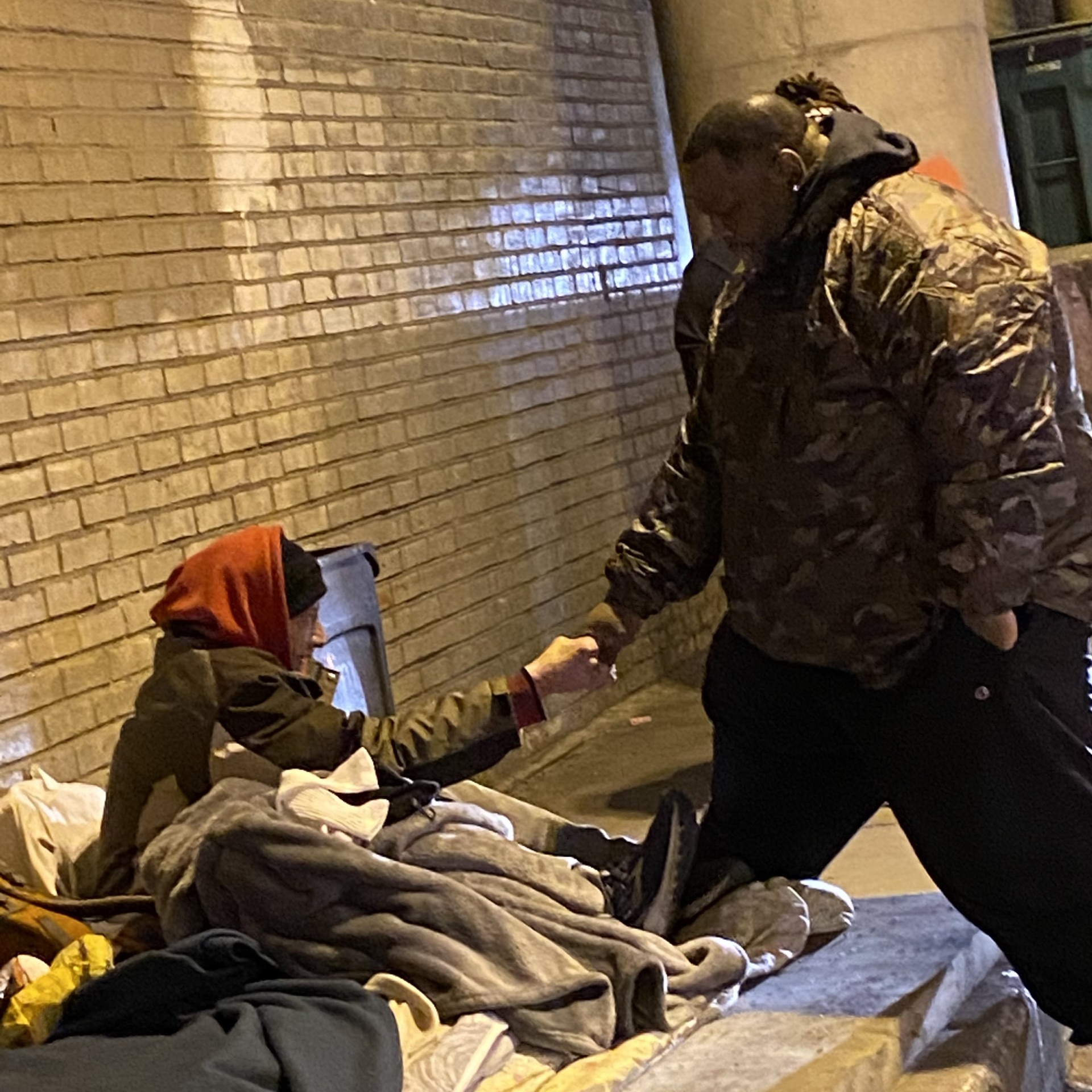Stringer Harris holding a community member’s hand during outreach